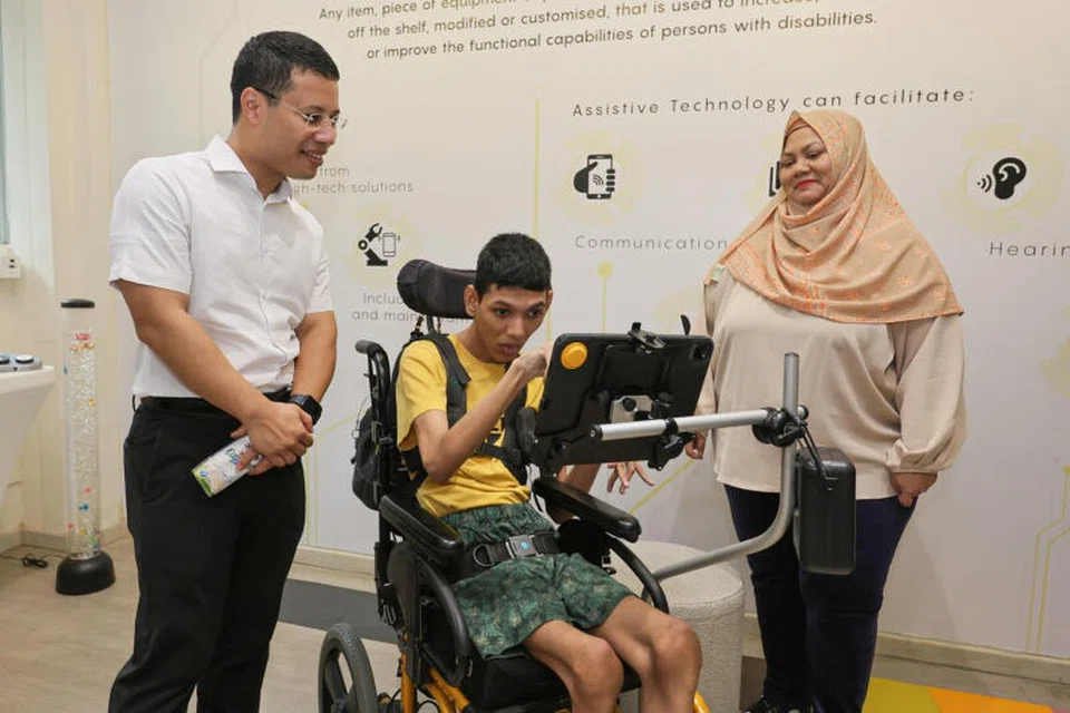 INTERAKSI BERSAMA: Encik Muhammad Sayfullah Mohamad Sahrin (tengah) berkomunikasi dengan Menteri Pembangunan Negara, Encik Desmond Lee, menggunakan alat komunikasi augmentatif dan alternatif sambil diperhatikan ibunya, Cik Siti Fadillah Mohamed Noor. Mereka menyertai acara National CARECarnival yang diadakan di Enabling Village di Lengkok Bahru pada Sabtu.