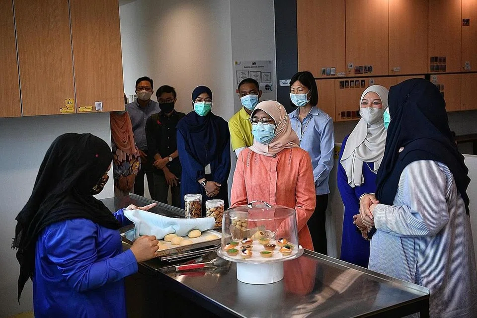 DEKATI MASYARAKAT: Puan Halimah (tengah), yang diiringi Cik Faraliza (dua dari kanan), meninjau-ninjau premis cawangan Changi Hab MIJ yang diperluas semalam dan berpeluang berinteraksi dengan golongan berkeperluan khas yang mendapatkan khidmat pusat tersebut. - Foto BH oleh ARIFFIN JAMAR