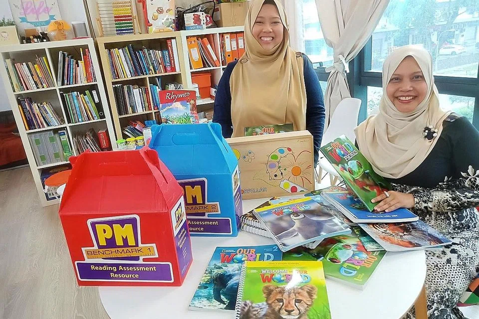 PEMANGKIN BUDAYA MEMBACA: Cik Hanisnah (duduk) dan Cik Haryani melakar program bagi membantu golongan buta huruf dan sukar membaca di pusat literasi mereka di Jalan Pemimpin dekat Upper Thomson Road. - Foto BH oleh SAINI SALLEH