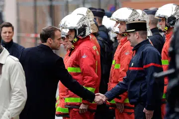 KUNJUNGI TEMPAT KEJADIAN: Presiden Perancis Emmanuel Macron (kiri) berjabat tangan dengan seorang anggota bomba semasa mengadakan lawatan di Paris menyusuli rusuhan oleh kumpulan antipemerintah yang membantah kenaikan cukai bahan bakar. - Foto AFP