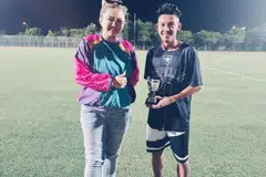 ANJUR LIGA BOLA DEMI SOKONG SUAMI: Penganjur liga Cik Nurul Natasha, 37 tahun (kiri) menghulurkan trofi kepada pemain terbaik Muhammad Azrin, 26 tahun (kanan).
