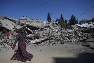 Wanita Palestin berjalan di sebelah rumah yang musnah berikutan operasi tentera Israel di kem pelarian Al Maghazi, selatan Semenanjung Gaza, pada 17 Februari.