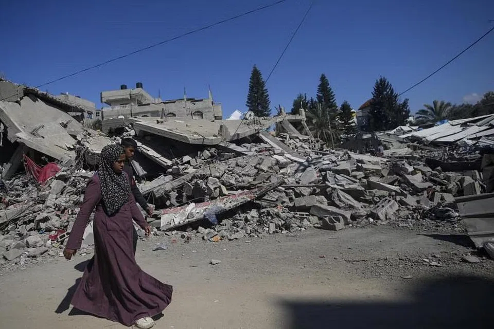 Wanita Palestin berjalan di sebelah rumah yang musnah berikutan operasi tentera Israel di kem pelarian Al Maghazi, selatan Semenanjung Gaza, pada 17 Februari.