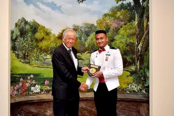 CEMERLANG: Mejar Mohamed Firdaus (kanan) menerima anugerah daripada Dr Ng dalam satu majlis di Istana kelmarin. - Foto MINDEF