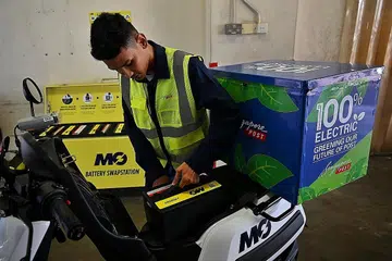MUDAH GANTI: Seorang pekerja penghantaran SingPost kelihatan mengeluarkan bateri motosikal elektrik baru dilancarkan semalam dalam satu percubaan motosikal dilengkapi teknologi mudah ganti bateri. - Foto ST
