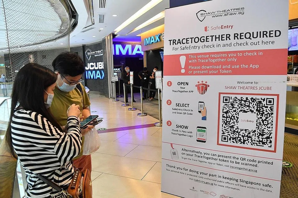 DAFTAR MASUK: Pengunjung pawagam Shaw Theatres di JCube kelihatan menggunakan aplikasi TraceTogether untuk mendaftar sebelum memasuki ruang panggung. - Foto fail