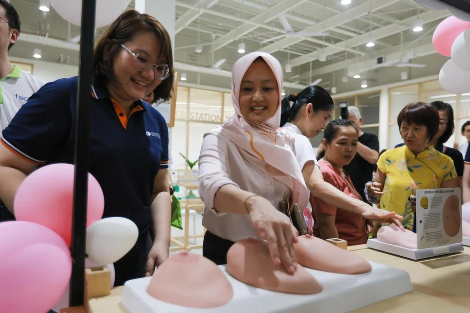 CARA PEMERIKSAAN: Cik Gwee Yu Im (kiri), jururawat staf kanan di Poliklinik Yishun bersama Setiausaha Parlimen Kanan (Kesihatan merangkap Undang-Undang), Cik Rahayu Mahzam, menyertai kegiatan seperti mengesan gumpalan pada model payu dara di salah satu reruai Karnival Bulan Kesedaran Barah Buah Dada 2023 di Pusat Belia Kemanusiaan Tzu Chi pada 1 Oktober 2023. 