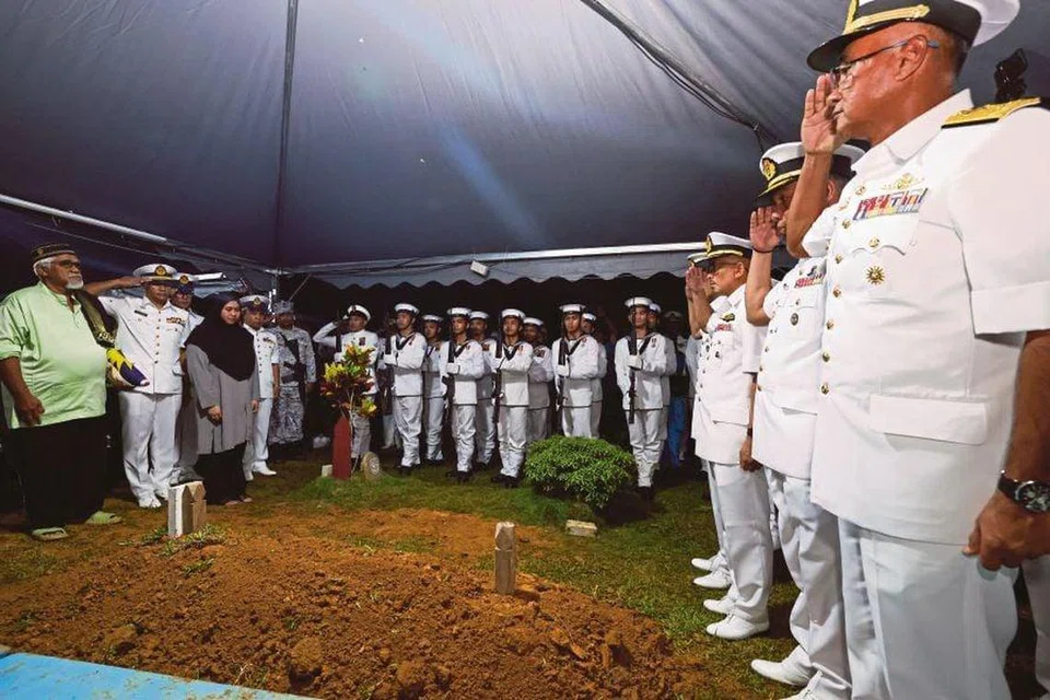 Bapa Allahyarham Komander Muhamad Amir Mohamad, Encik Mohamad Borak, 71 tahun (kiri), menerima tabik hormat daripada anggota Tentera Laut Diraja Malaysia (TLDM) ketika upacara pengebumian anaknya di Tanah Perkuburan Islam Felcra Bukit Kepong, Muar, Johor, pada 24 April.