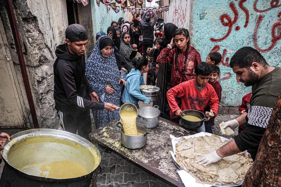 Para penduduk Palestin yang berlindung di Rafah, selatan Gaza, beratur bagi mendapatkan makanan berbuka puasa yang diagihkan oleh sebuah badan amal.