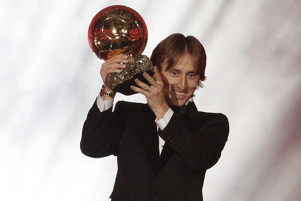 TERBAIK DUNIA: Luka Modric (atas) menjulang trofi Ballon d'Or sebagai pemain terbaik dunia buat kali pertamanya tahun ini menyusuli kecemerlangannya di peringkat kelab dan juga membantu negaranya, Croatia, mara sehingga ke final Piala Dunia Russia pada Jun-Julai lalu. - Foto REUTERS
