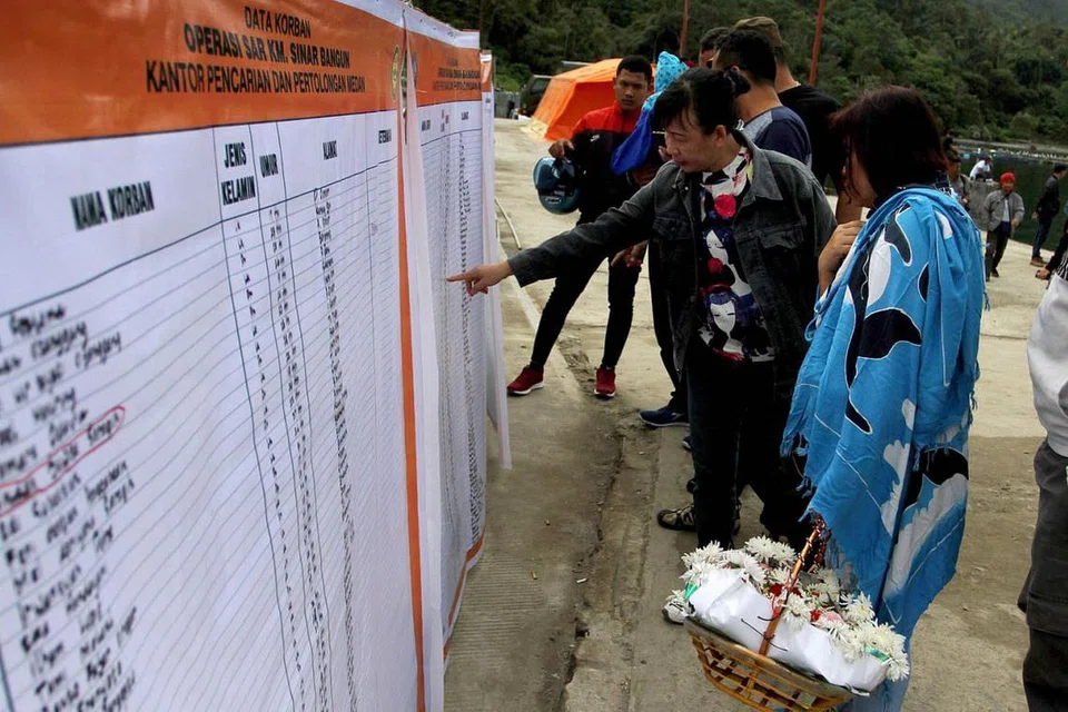 SENARAI MANGSA: Saudara mara dan ahli keluarga mangsa kapal karam di Danau Toba meneliti nama-nama mangsa yang tersenarai. Seramai 193 penumpang berada dalam kapal KM Sinar Baru yang terbalik dan tenggelam semasa dalam pelayaran dari Pelabuhan Simanindo ke Pelabuhan Tigaras di Simalungun, kedua-duanya di Sumatera Utara. - Foto AFP