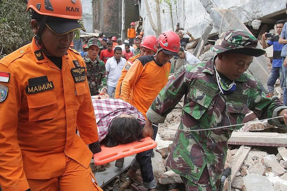 DISELAMATKAN: Seorang mangsa berjaya ditarik keluar daripada runtuhan bangunan di daerah in Ulee Glee, Pidie Jaya, dan dikejarkan ke hospital. - Foto REUTERS