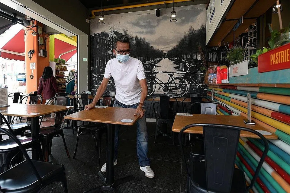 BUAT PENYESUAIAN: Seorang pekerja I am Cafe menyusun semula meja dan kerusi kafe itu untuk menyambut tetamu dalam bilangan lebih kecil mulai hujung minggu ini. - Foto BH oleh NG SOR LUAN