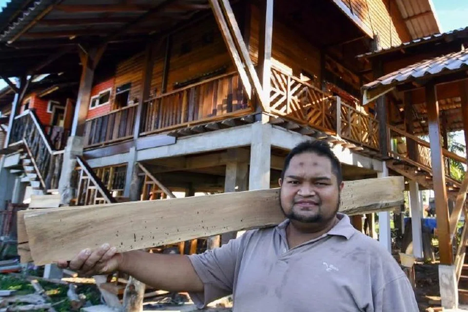 PUAS HATI: Mohd Nazmie Che Mohd Ashari, 37 tahun, berdiri di hadapan rumahnya yang dibina sendiri daripada kayu yang terbuang di Pantai Senok, Bachok, Kelantan.