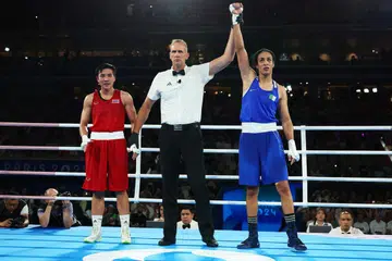 Pengadil perlawanan, Shawn Reese (tengah), mengangkat tangan petinju Imane Khelif (kanan), untuk mengisytiharkan beliau sebagai pemenang dalam pertarungan menentang Janjaem Suwannapheng dari Thailand. 