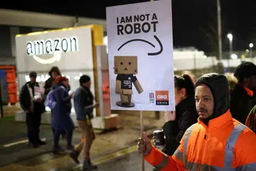 PERTIKAI GAJI:  Seorang lelaki memegang papan tanda semasa perhimpunan untuk menyokong pekerja Amazon yang mogok, di luar gudang Amazon di Coventry, Britain, pada 25 Januari 2023.