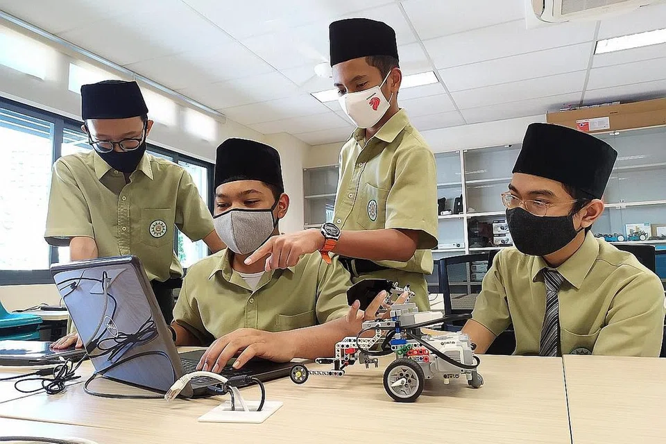 MENYEMAI MINAT BIDANG ROBOTIK: Para pelajar Madrasah Al-Arabiah Al-Islamiah, (dari kiri) Muhammad Luqman Al-Hakim Muhammad Faizal, Muhammad Afiq Hadi Putra Azhar, Alfi Nurrahman dan Ahmad Hasbi Huzaimi, menduduki tempat kedua, Anugerah Penyelidikan, di pertandingan robotik FIRST LEGO League Sg baru-baru ini. - MADRASAH AL-ARABIAH AL-ISLAMIAH