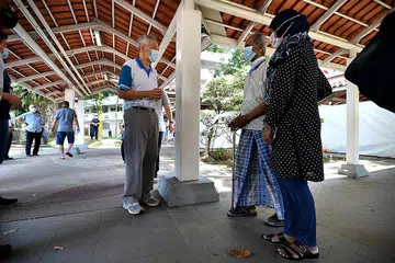 SAPA PENDUDUK: PM Lee berbual dengan penduduk yang telah menjalani ujian swab di laluan berbumbung dekat Blok 460A Ang Mo Kio Avenue 10 semalam. Kelmarin, beliau menggalak warga emas yang belum mendapatkan vaksin Covid-19 supaya mendapatkannya dengan segera agar tidak terlewat. - Foto BH oleh LIM YAOHUI