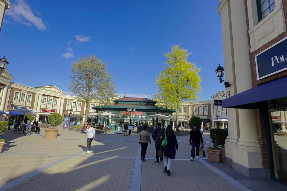 Pemandangan pusat beli-belah di McArthurGlen Designer Outlet Vancouver Airport yang sibuk dengan pengunjung yang sedang menikmati suasana cerah dan nyaman.