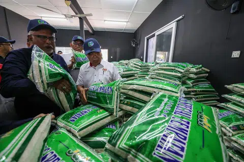 BEKALAN CUKUP: Menteri Pertanian dan Keterjaminan Makanan Datuk Seri Mohamad Sabu (kanan) melihat beras tempatan yang akan dijual kepada orang ramai menerusi Program Jualan Agro Madani pada Jumaat.