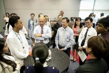 LATIHAN AMALI DIPERTINGKAT: Pengerusi Lembaga Gabenor ITE, Encik Bob Tan (bertali leher merah); Pengarah dan Ketua Pegawai Eksekutif ITE, Encik Bruce Poh (bertali leher kelabu); dan Pengetua ITE Kolej Barat, Dr Goh Mong Song (bertali leher hitam), berinteraksi dengan pelatih ITE di syarikat NCS. - Foto ITE