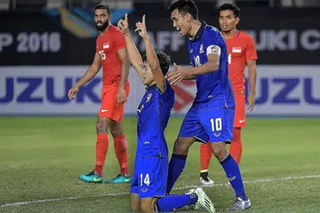 RAIKAN GOL: Pemain gantian Thailand Sarawut Masuk (nombor 14) meraikan gol jaringannya ke atas Singapura bersama kaptennya, Teerasil Dangda. Thailand mengalahkan Singapura 1-0 dalam perlawanan Kumpulan A Piala Suzuki AFF di Stadium Sukan Filipina semalam. - Foto THE STRAITS TIMES