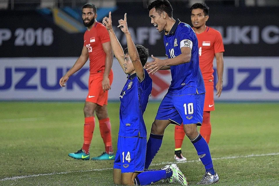 RAIKAN GOL: Pemain gantian Thailand Sarawut Masuk (nombor 14) meraikan gol jaringannya ke atas Singapura bersama kaptennya, Teerasil Dangda. Thailand mengalahkan Singapura 1-0 dalam perlawanan Kumpulan A Piala Suzuki AFF di Stadium Sukan Filipina semalam. - Foto THE STRAITS TIMES