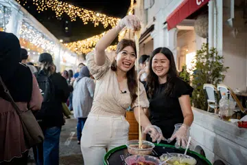 Wartawan ruangan, Kaki Makan, Cik Dahlia Zulkifli (kiri), dan Editor dalam Talian, Straits Times Food, Cik Eunice Quek, mencuba pelbagai makanan dan minuman menarik di Bazar Kampong Gelam, antaranya hidangan kroisan tarik yang disumbat dengan keju dan dibanjiri sos coklat.