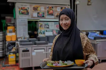 KINI USAHAWAN BERJAYA: Faridah Dollah kini gigih mengendalikan perniagaan Syifa’ Satay di Makansutra Gluttons Bay dan menyediakan pelbagai juadah kepada pelanggan. 