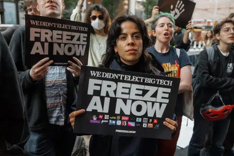 Penunjuk perasaan memegang sepanduk bertulis ‘We Didn’t Elect Big Tech, Freeze AI Now’ (“Kami tidak memilih syarikat teknologi gergasi, hentikan pembangunan AI sekarang.”) ketika menyertai perhimpunan membantah kecerdasan buatan (AI) di luar bangunan yang menempatkan pejabat OpenAI di SoHo, New York, pada 20 Oktober 2026. New York kini memperkenalkan undang-undang baru yang melarang chatbot AI bertindak sebagai teman peribadi kepada pengguna bawah 18 tahun, selain mewajibkan pengesahan usia bagi melindungi kanak-kanak dan remaja daripada risiko pergantungan emosi terhadap teknologi tersebut.