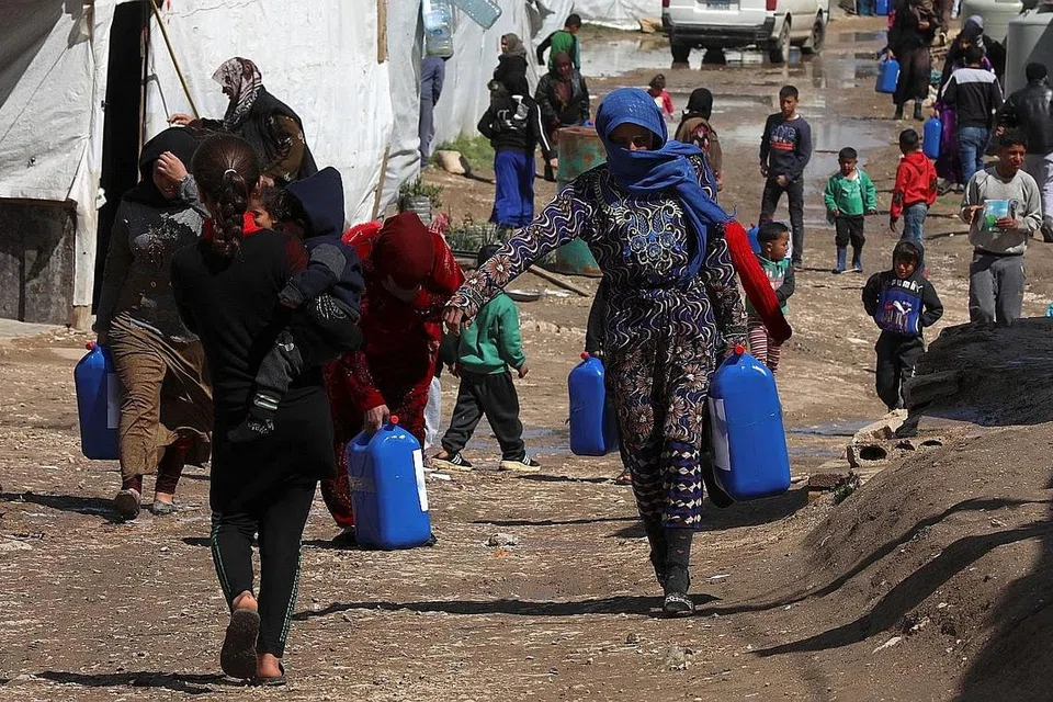 MAKIN RAMAI PERLU BANTUAN: Pelarian Syria berjalan sambil membawa kontena di sebuah kem tidak rasmi di lembah Bekaa, Lebanon. Kira-kira 24 juta rakyat Syria memerlukan bantuan kemanusiaan asas, bertambah seramai empat juta orang sepanjang setahun lalu. - Foto REUTERS