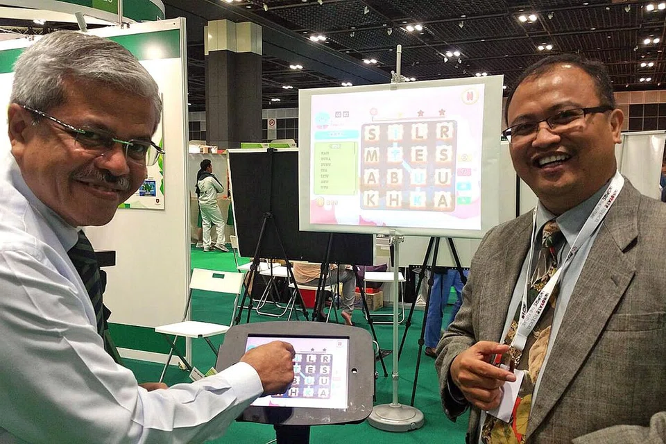 LUASKAN KOSA KATA: Encik Mohamed Noh Daipi (kiri) dan Encik Rahmat Subadah sedang menunjukkan bagaimana aplikasi Pintar Kata dapat meluaskan kosa kata pelajar yang menggunakannya. - Foto SHAHIDA SARHID