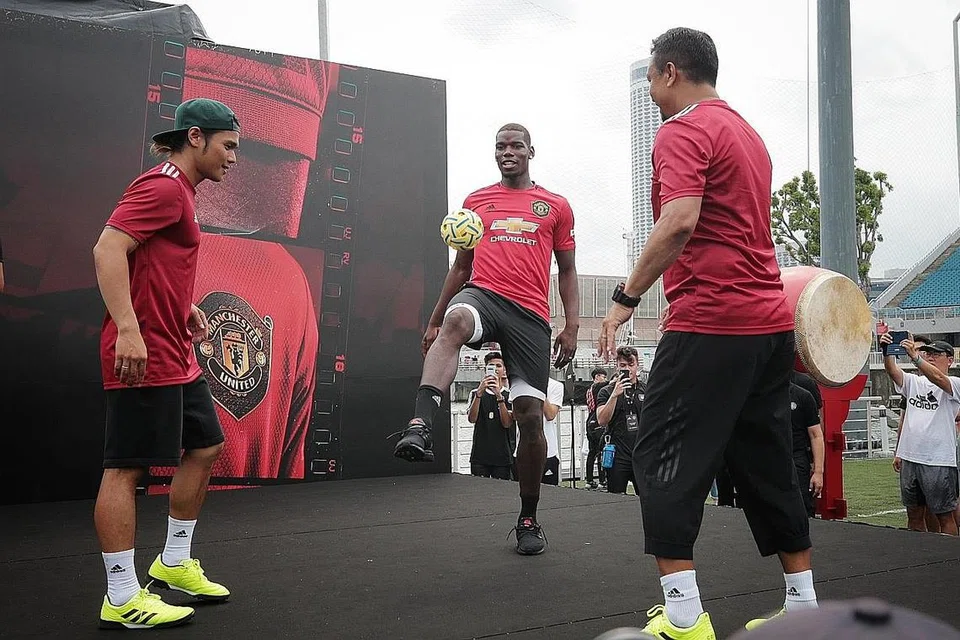 CUBA SUKAN SETEMPAT: Pogba (tengah) menguji ketangkasan dirinya menimbang bola sepak takraw sambil disaksikan ikon bola sepak negara, Fandi Ahmad (kanan), dan artis bola sepak 'freestyle' Terence Ong dari Urban Street Team. - Foto BH oleh JASON QUAH