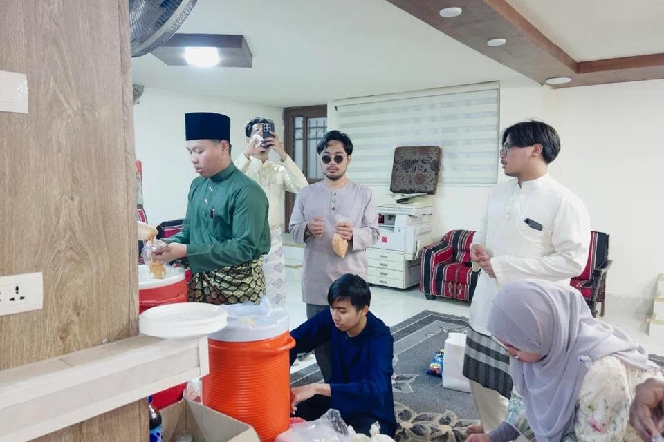 Penulis, Encik Muhammad Firdaus Norzulaini (kiri), bersama teman-temannya membungkus air untuk dibawa pulang dari majlis Perjumpaan Hari Raya pada 22 Mac.