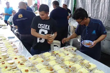 TRADISI MASJID: Para sukarelawan dari Masjid Khalid turut meringankan tangan membungkus nasi beriani sewaktu acara Cabaran Presiden kelmarin. Menurut Pengerusi Masjid Khalid, Encik Allaudin Mohamed, Nasi Beriani sering mendapat sambutan yang amat menggalakkan bagi acara mengumpul derma masjid kerana ia memiliki rasa yang unik dan tahan lama. - Foto ALLAUDIN MOHAMAD