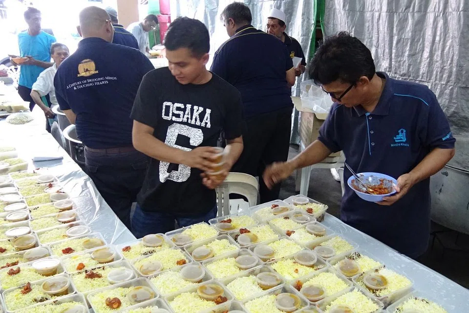 TRADISI MASJID: Para sukarelawan dari Masjid Khalid turut meringankan tangan membungkus nasi beriani sewaktu acara Cabaran Presiden kelmarin. Menurut Pengerusi Masjid Khalid, Encik Allaudin Mohamed, Nasi Beriani sering mendapat sambutan yang amat menggalakkan bagi acara mengumpul derma masjid kerana ia memiliki rasa yang unik dan tahan lama. - Foto ALLAUDIN MOHAMAD