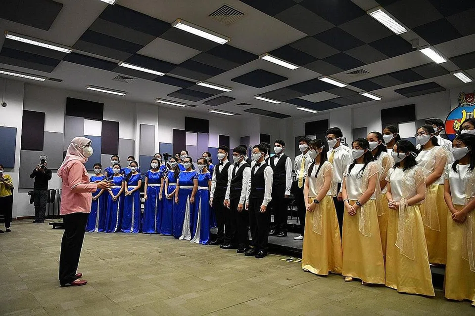KOIR MAYA: Presiden Halimah Yacob (kiri) mengunjungi sesi latihan dan rakaman bunyi kumpulan koir seramai 95 peserta yang akan menyanyikan lagu tema NDP, 'Stronger Together'. dengan rendisi sendiri semasa segmen perbarisan dan akan disiarkan secara maya pada 9 Ogos nanti. Dalam gambar, Puan Halimah sedang berinteraksi dengan sebahagian daripada anggota kumpulan koir itu. - Foto MINDEF