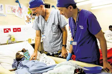 MENYUMBANG KHIDMAT: Ketua Pegawai Perubatan Africa Mercy, Dr Gary Parker (kiri), bersama pakar bedah sukarelawan Encik Leo Cheng daripada United Kingdom melawat pesakit yang telah mendapat pembedahan di atas kapal hospital awam terbesar di dunia. - Foto MERCY SHIPS / DEBRA BELL