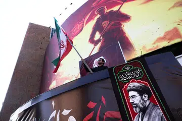 Seorang lelaki memegang bendera Iran bersebelahan gambar Pemimpin Tertinggi Iran, Ayatollah Mojtaba Khamenei, di Teheran pada 13 Ogos 2026. Tempoh 60 hari yang diberikan kepada Iran dan Amerika Syarikat untuk merundingkan perjanjian muktamad berakhir pada 17 Ogos tanpa penyelesaian, dengan kedua-dua pihak masih berselisih mengenai pembukaan semula Selat Hormuz, sekatan ekonomi dan program nuklear Teheran.