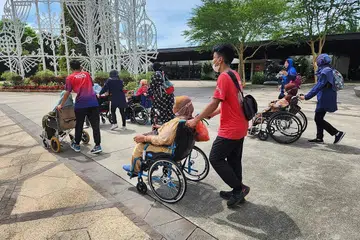BELIA HARAPAN BANGSA: Para sukarelawan belia ini membantu penduduk berkeperluan khas dari Teban Gardens ketika melawat ke tempat menarik, Gardens By The Bay, anjuran Masjid Hasanah pada Selasa lalu. - Foto MASJID HASANAH