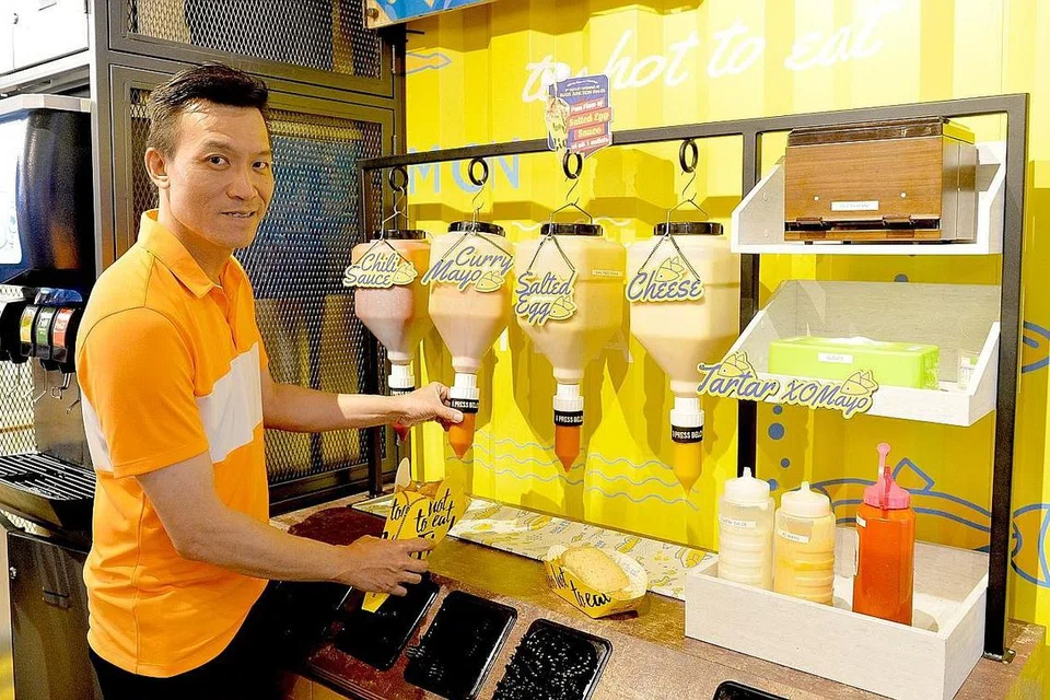 PELBAGAI PILIHAN IKAN DAN SOS: Pengasas bersama Big Fish Small Fish, Encik Tham Kok Yun, memilih salah satu daripada tujuh sos dan cecahan yang disediakan di kafe itu secara free flow untuk dinikmati bersama hidangan Fish & Crisps. Foto BM oleh KHALID BABA