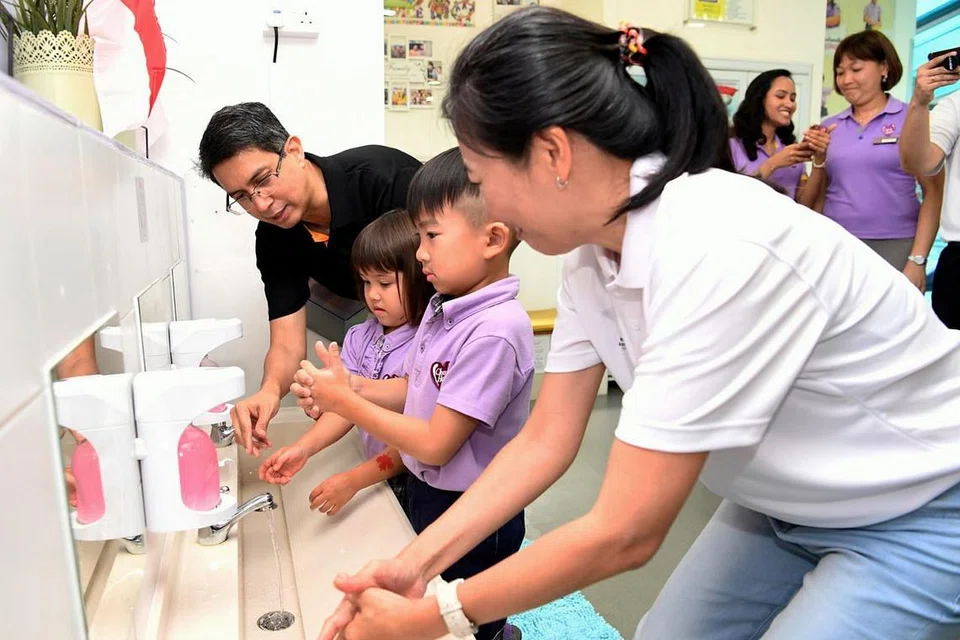 JAGA KEBERSIHAN DI TANDAS: Dr Faishal (kiri) menyaksikan murid prasekolah menunjukkan cara mencuci tangan yang betul di tandas. Beliau berada di majlis pelancaran buku oleh Persatuan Tandas Singapura (RAS) sempena ulang tahun ke-20 semalam. - Foto BH oleh KHALID BABA