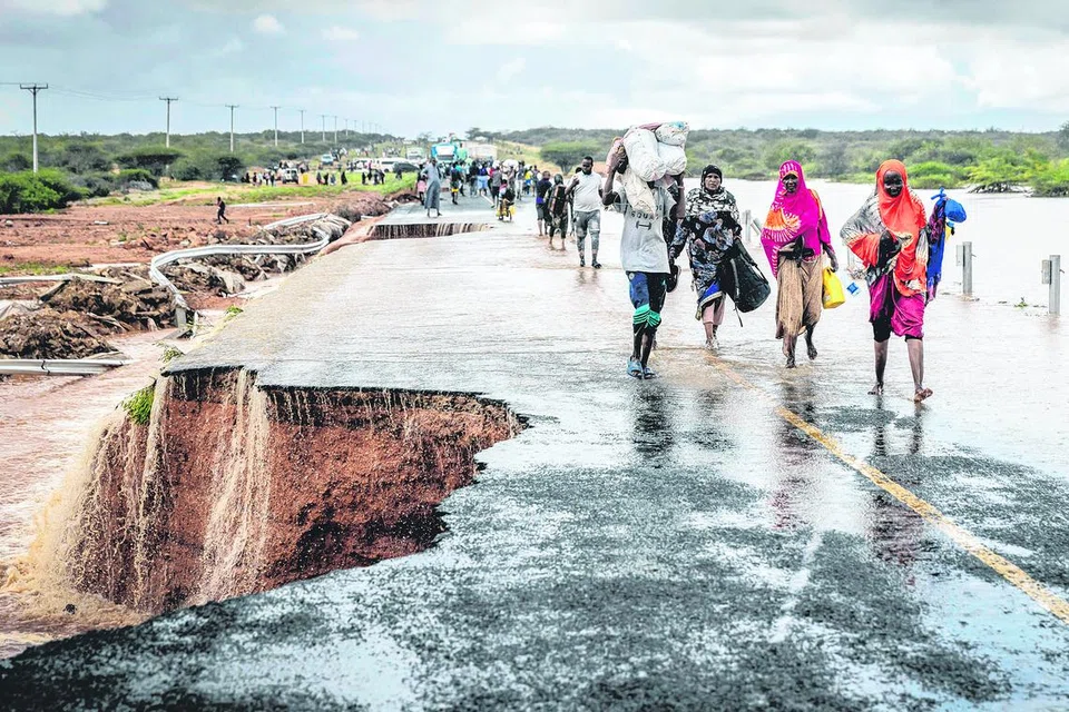PELARIAN PERUBAHAN IKLIM: Orang ramai membawa barang-barang mereka semasa melintasi bahagian jalan yang runtuh akibat banjir kilat di Jalan Mwingi-Garissa berhampiran Garissa,  Afrika Timur, 22 November 2023.