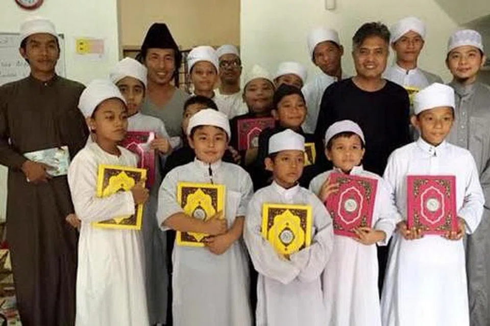 AMALAN IKUT KEMAMPUAN: Penyanyi rok Amy (bersongkok hitam barisan belakang) bergambar bersama 15 pelajar sekolah tahfiz yang dibukanya bersama seorang teman di Sungai Buloh. - Foto MSTAR