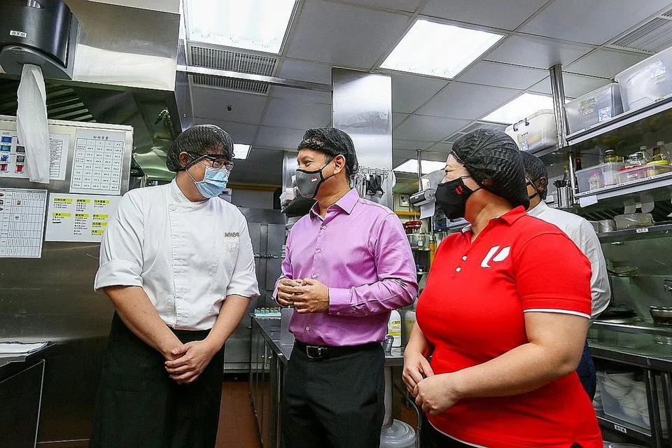 DEMI JAGA KEBAJIKAN PEKERJA BERGAJI RENDAH: Encik Zaqy Mohamad (tengah) dan pengarah U SME, Cik Yeo Yan Ling, mengunjungi restoran Jumbo Seafood di Upper Circular Road semalam, untuk memahami lebih baik rintangan dalam usaha mempertingkat pekerja bergaji rendah dalam sektor perkhidmatan makanan. - Foto ZAOBAO