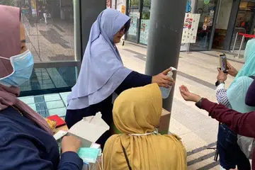 GOTONG-ROYONG: Beberapa warga Indonesia bergotong-royong membahagi-bahagikan pelitup dan snek kepada orang ramai di kawasan Payar Lebar pada Ahad (9 Februari).