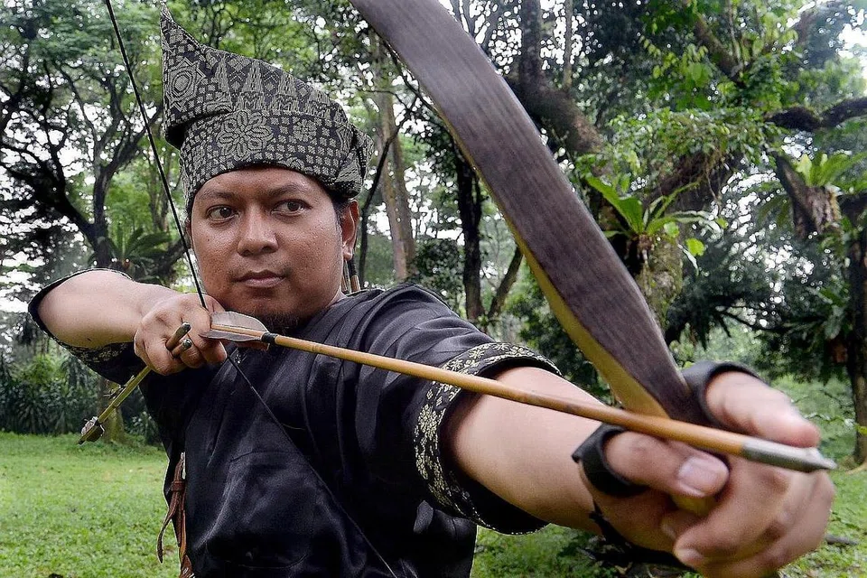 SENAMAN HARIAN: Selepas membaca Al-Quran setiap pagi, Ustaz Fachruddin Dzaki akan meluangkan masa sekurang-kurangnya setengah jam menarik sejenis getah senaman untuk memperkuat otot lengan, bahu dan belakangnya. Ini akan menambah kekuatannya menarik busur panah selain salah satu bentuk senaman yang diamalkan untuk menjaga kesihatannya. - Foto ihsan USTAZ FACHRUDDIN DZAKI dan fail