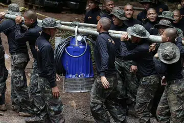 BERTUNGKUS LUMUS: Pegawai tentera Thailand semalam mengusung mesin pam air ke mulut Gua Tham Luang, Chiang Rai, demi menyelamatkan mangsa terperangkap. - Foto REUTERS