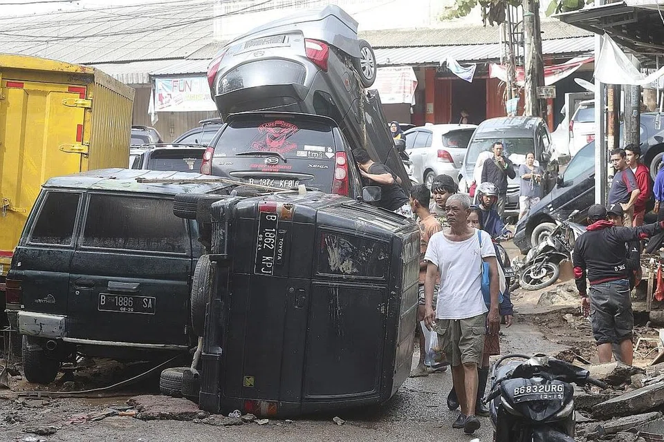 KESAN BANJIR...: HARTA BENDA ROSAK: Penduduk meninjau kenderaan yang dipukul banjir kilat di Bekasi, Jawa Barat di Indonesia. - Foto AP
