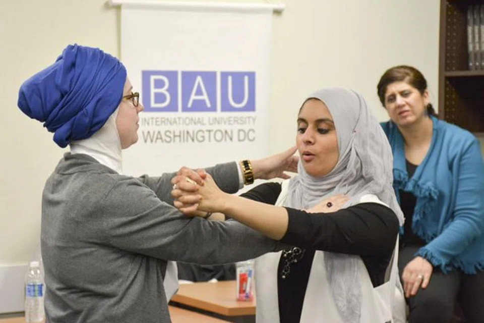 BELAJAR PERTAHAN DIRI: Cik Rana Abdelhamid (tengah) sedang menunjukkan satu teknik karate kepada Cik Kristin Garrity Sekerci dalam satu bengkel khusus untuk Muslimah di Washington. - Foto REUTERS